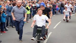 Competitors Race around Town in Mass Wheelbarrow Race [upl. by Ahasuerus]