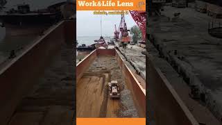 A bulldozer pushes stones into piles in a ships hull for a crane to load onto trucks [upl. by Gosser386]